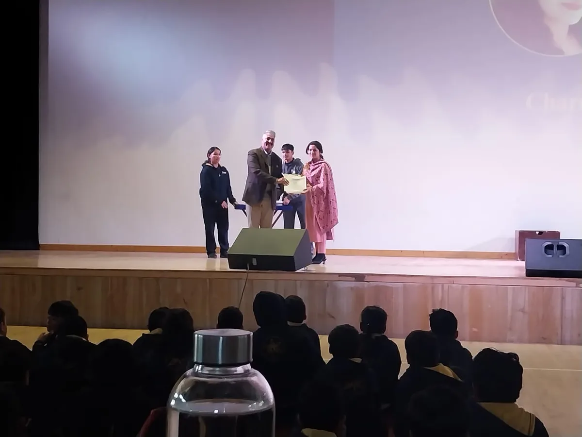Charu Wadhwa presenting on stage to a seated audience in an auditorium