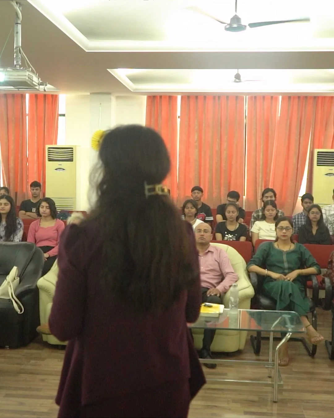 Charu Wadhwa addressing a full seminar hall of seated attendees
